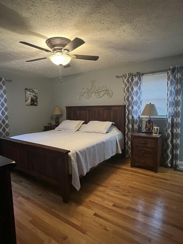 bedroom with a textured ceiling, hardwood / wood-style flooring, and ceiling fan