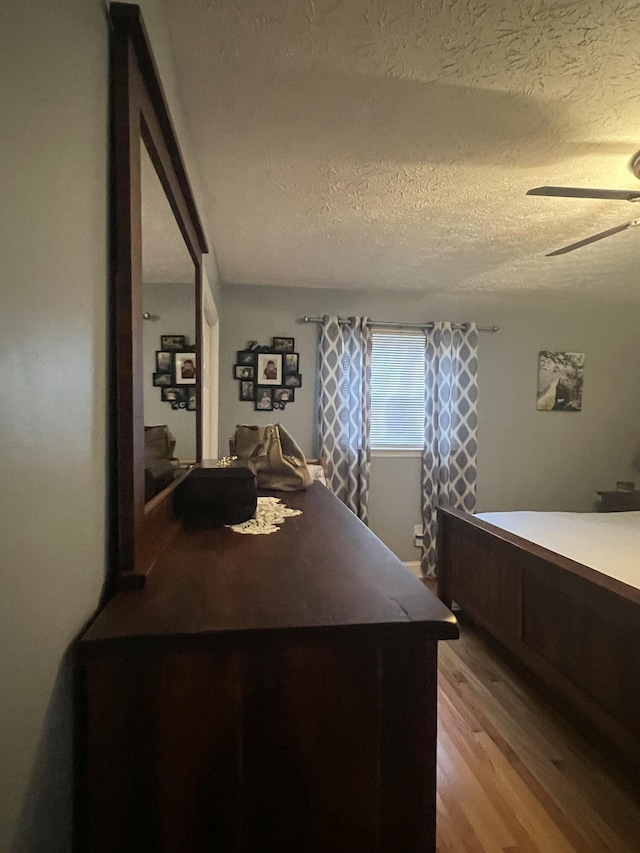 bedroom with ceiling fan, light hardwood / wood-style floors, and a textured ceiling