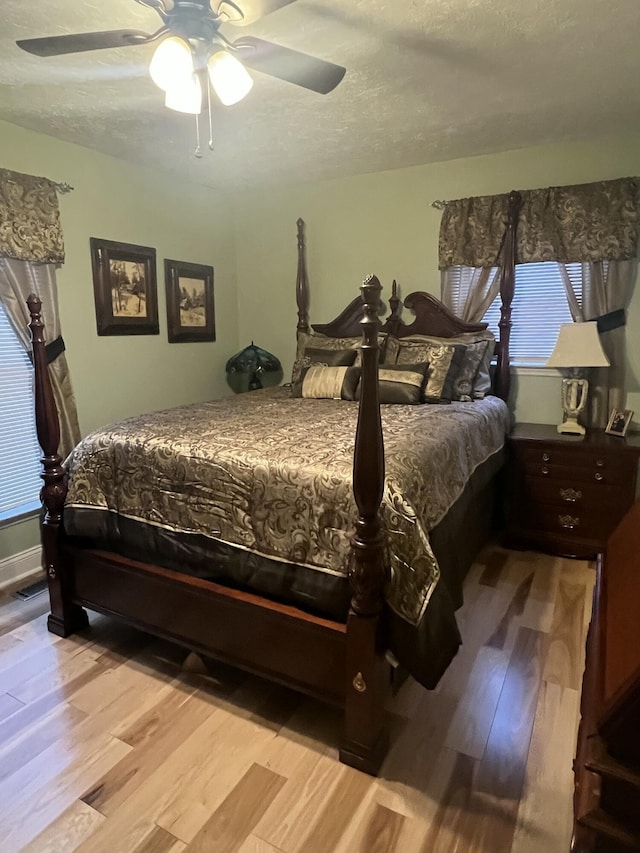 bedroom with ceiling fan, a textured ceiling, and light wood-type flooring