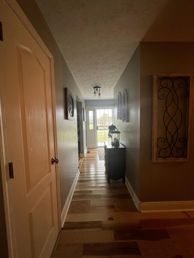 corridor featuring a textured ceiling and light hardwood / wood-style flooring