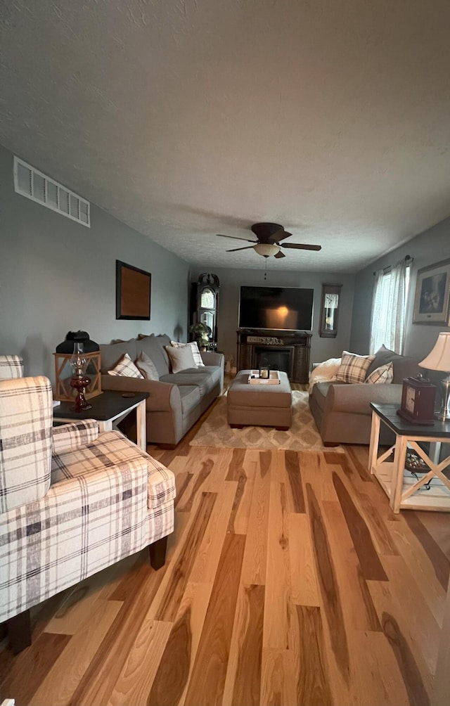 living room with hardwood / wood-style floors, a textured ceiling, and ceiling fan