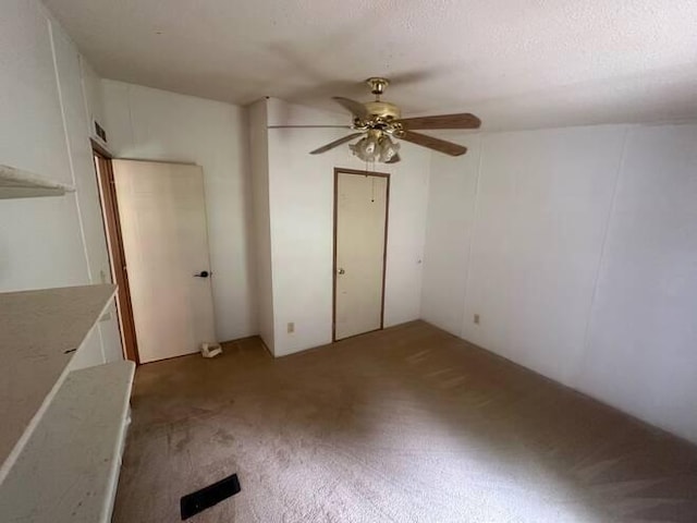 spare room featuring a textured ceiling, carpet floors, and ceiling fan