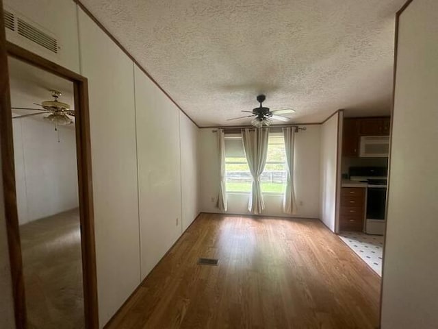 unfurnished room with ceiling fan, a textured ceiling, and light hardwood / wood-style flooring