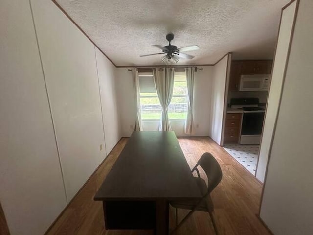 dining area featuring hardwood / wood-style flooring, ceiling fan, crown molding, and a textured ceiling