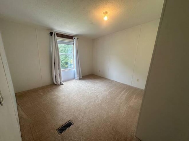 carpeted empty room with a textured ceiling