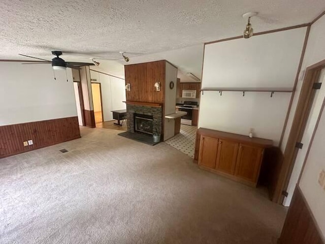 unfurnished living room featuring ceiling fan, a textured ceiling, wooden walls, and vaulted ceiling