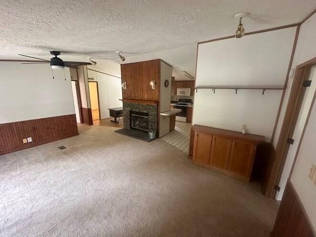 unfurnished living room featuring vaulted ceiling, wooden walls, ceiling fan, and a textured ceiling