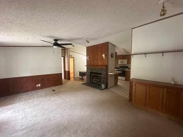 unfurnished living room featuring wooden walls, vaulted ceiling, ceiling fan, a textured ceiling, and light colored carpet