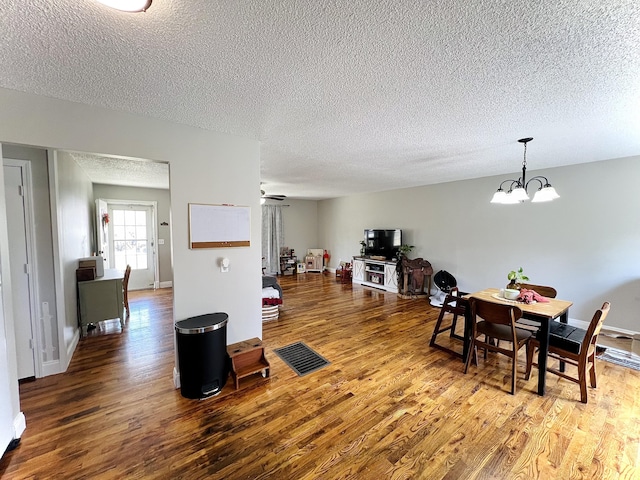 dining space featuring hardwood / wood-style flooring, ceiling fan with notable chandelier, and a textured ceiling