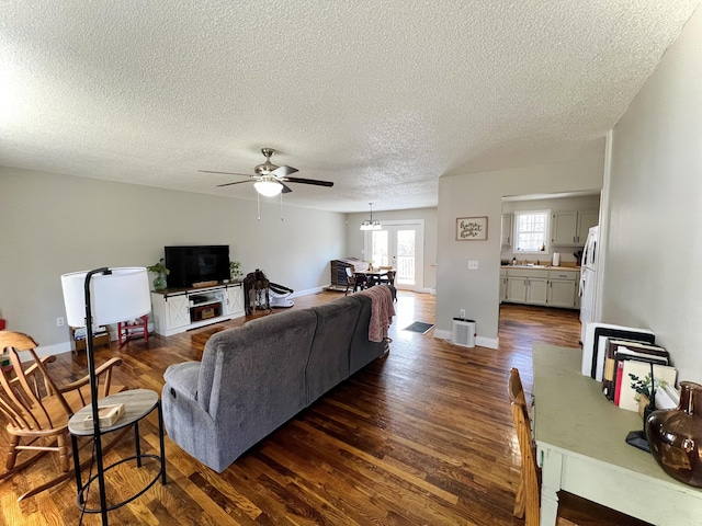 living room featuring a textured ceiling, dark wood-type flooring, and ceiling fan with notable chandelier