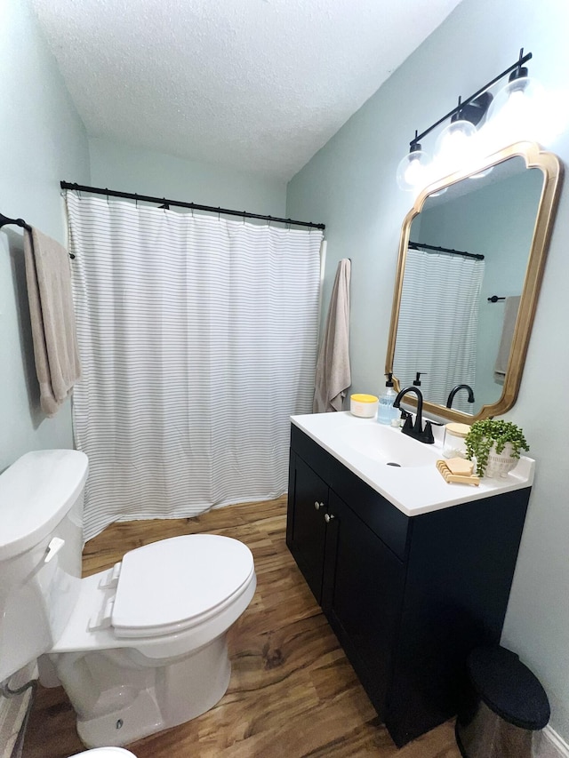 bathroom with toilet, vanity, a textured ceiling, and hardwood / wood-style flooring