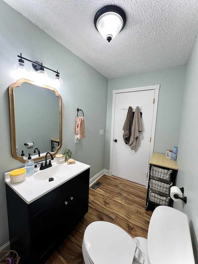 bathroom with vanity, wood-type flooring, a textured ceiling, and toilet