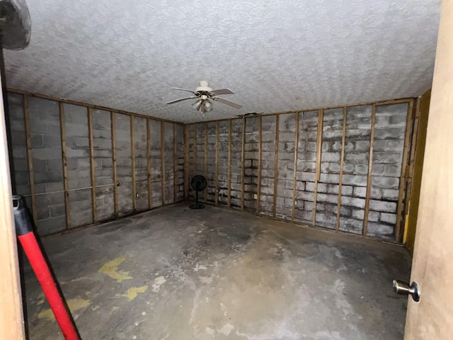 basement with ceiling fan and a textured ceiling