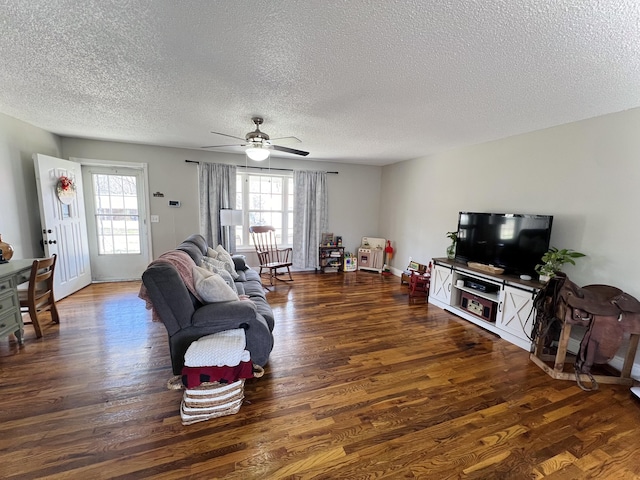 living room featuring ceiling fan, dark wood-type flooring, and a textured ceiling