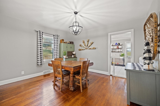 dining space featuring dark hardwood / wood-style flooring, plenty of natural light, and an inviting chandelier