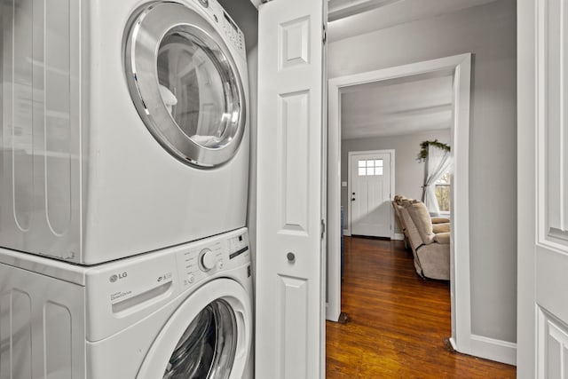 laundry room featuring dark hardwood / wood-style flooring and stacked washing maching and dryer