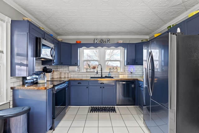 kitchen featuring blue cabinetry, stainless steel appliances, butcher block counters, and sink