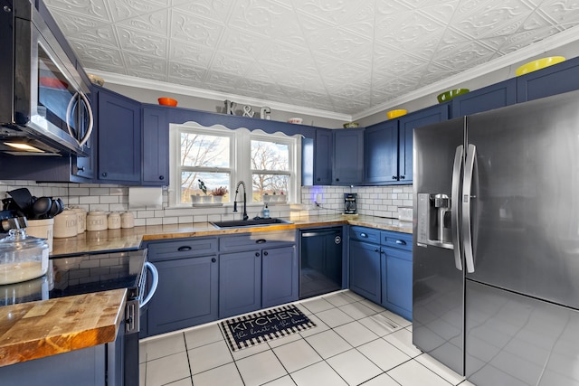 kitchen featuring wood counters, stainless steel appliances, and blue cabinetry