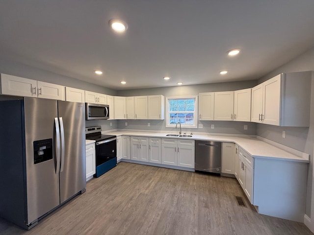 kitchen featuring sink, white cabinets, light wood-type flooring, and appliances with stainless steel finishes