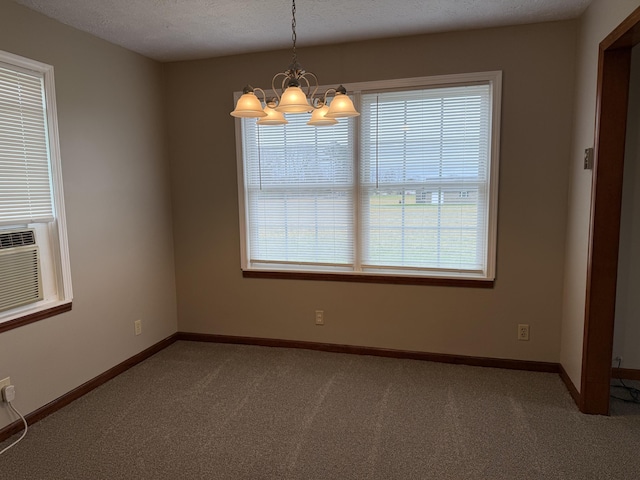 carpeted empty room with a textured ceiling and an inviting chandelier