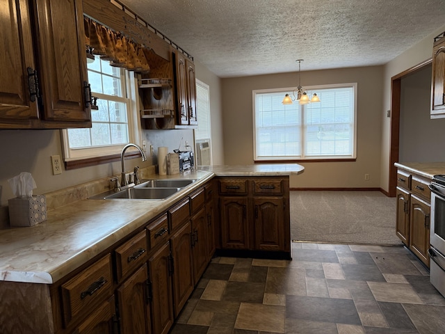 kitchen with plenty of natural light, sink, decorative light fixtures, kitchen peninsula, and a chandelier