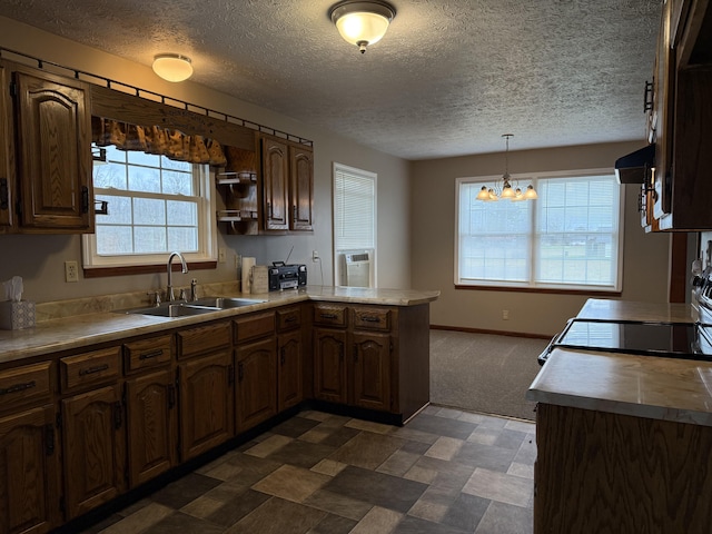 kitchen featuring kitchen peninsula, ventilation hood, sink, decorative light fixtures, and a notable chandelier