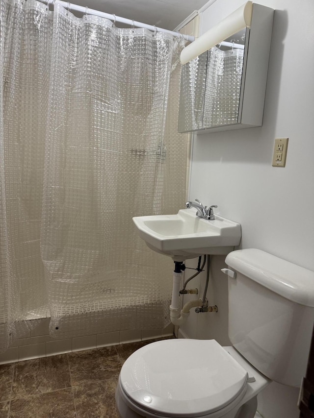 bathroom featuring curtained shower, toilet, and sink