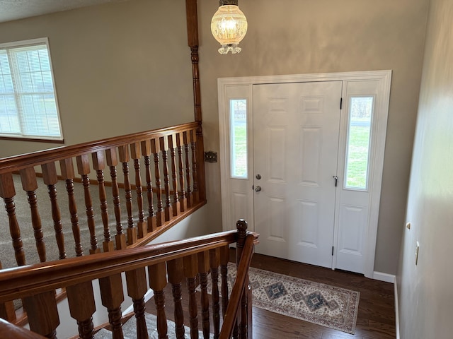 entrance foyer with a healthy amount of sunlight, dark wood-type flooring, and a chandelier