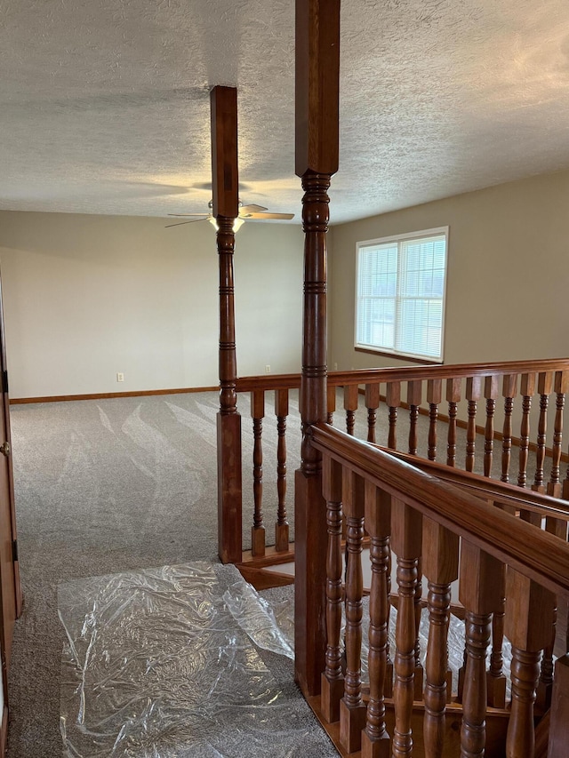 stairway with a textured ceiling and carpet floors