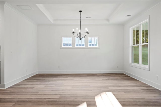 unfurnished dining area featuring a chandelier, light wood-type flooring, and a tray ceiling