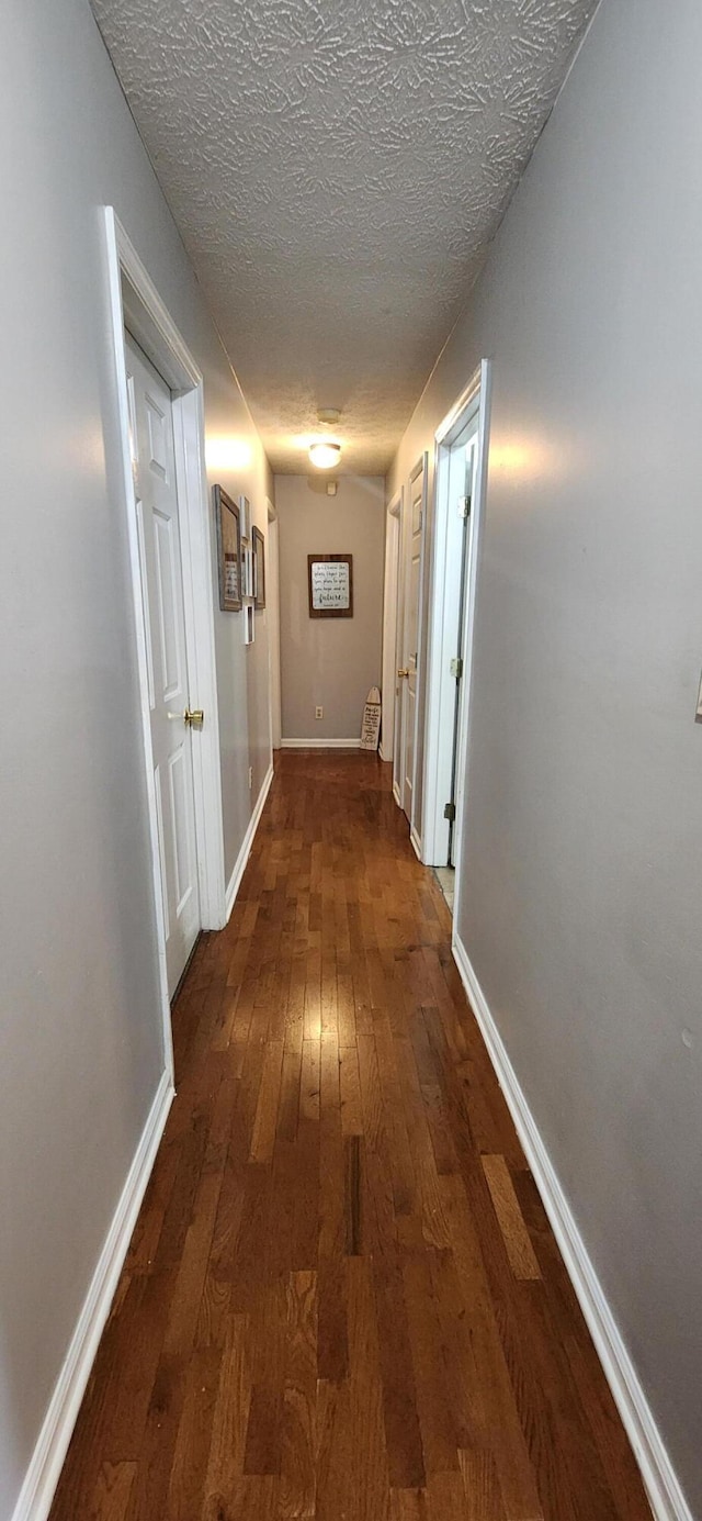 hall featuring a textured ceiling and dark hardwood / wood-style floors