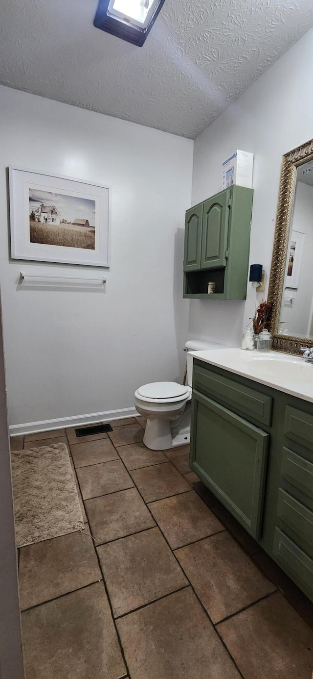 bathroom featuring vanity, a textured ceiling, and toilet