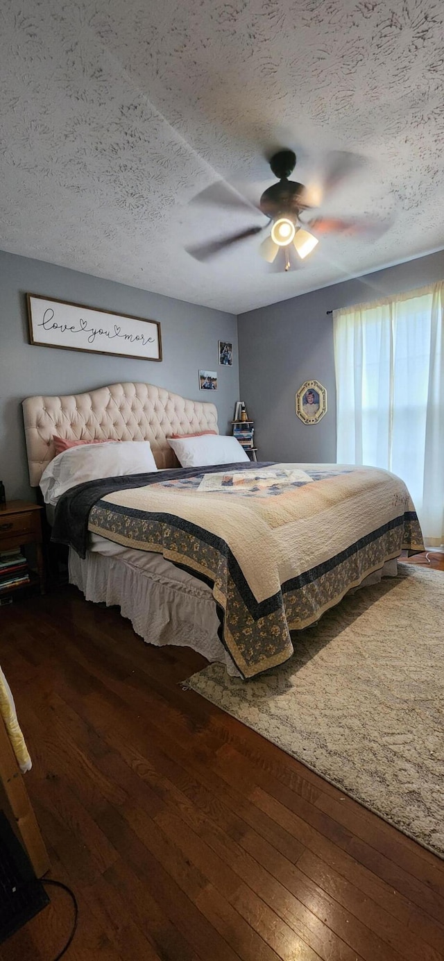 bedroom with ceiling fan, dark hardwood / wood-style floors, and a textured ceiling