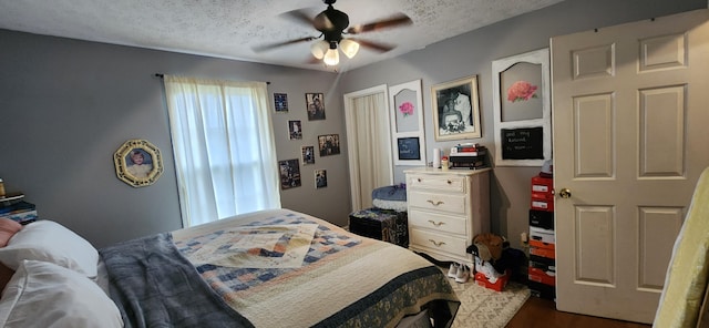 bedroom featuring ceiling fan, dark hardwood / wood-style flooring, and a textured ceiling