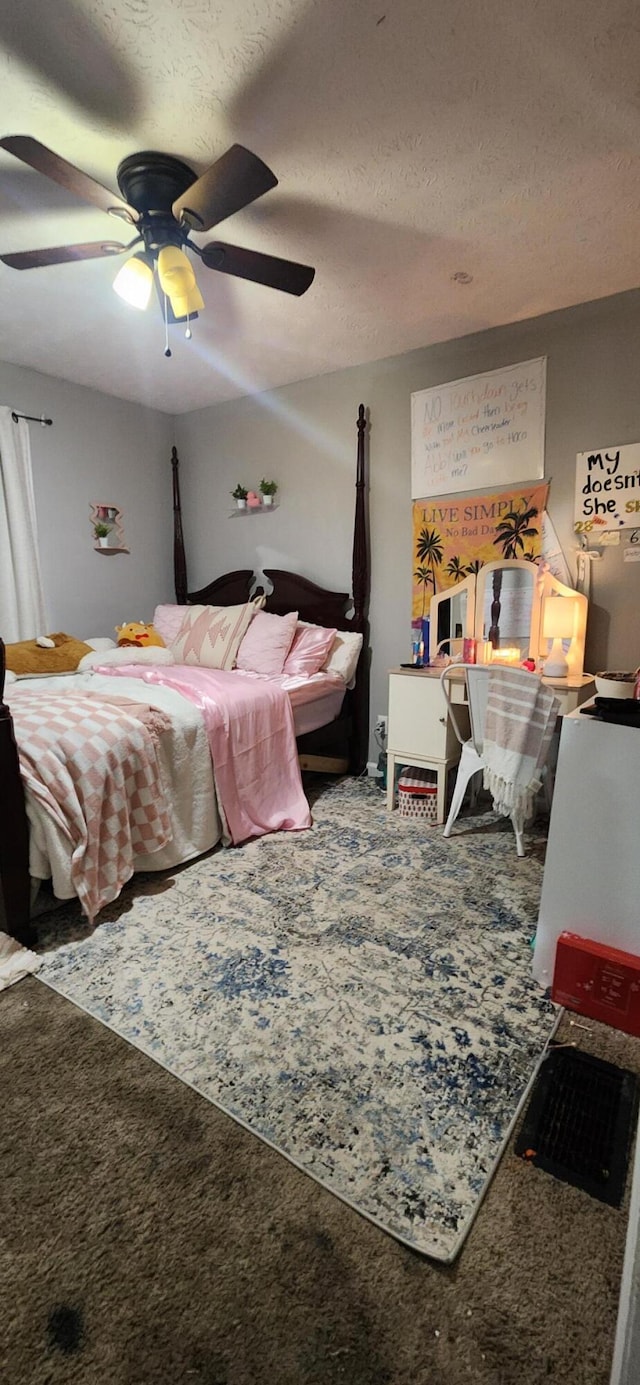 carpeted bedroom with ceiling fan and a textured ceiling