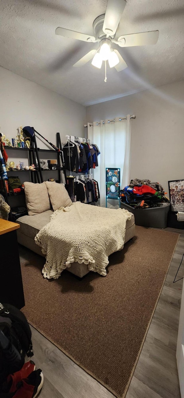 bedroom with ceiling fan, wood-type flooring, and a textured ceiling