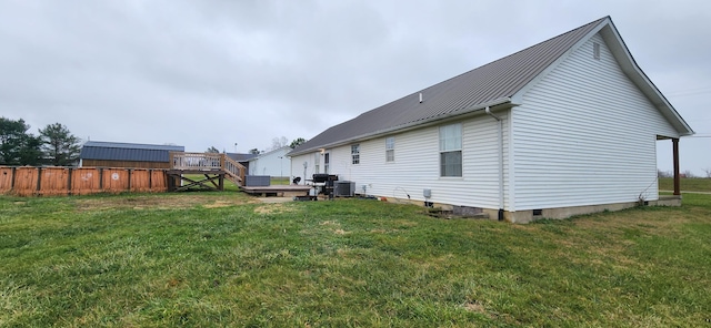 rear view of property featuring a lawn, cooling unit, and a wooden deck