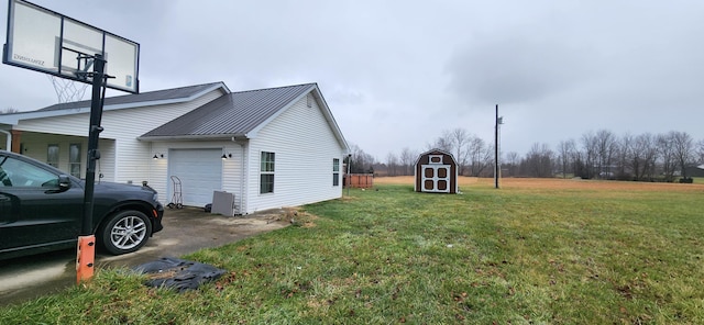 view of side of home with a yard, a garage, and a shed