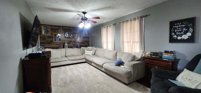 living room with ceiling fan, a textured ceiling, and wooden walls