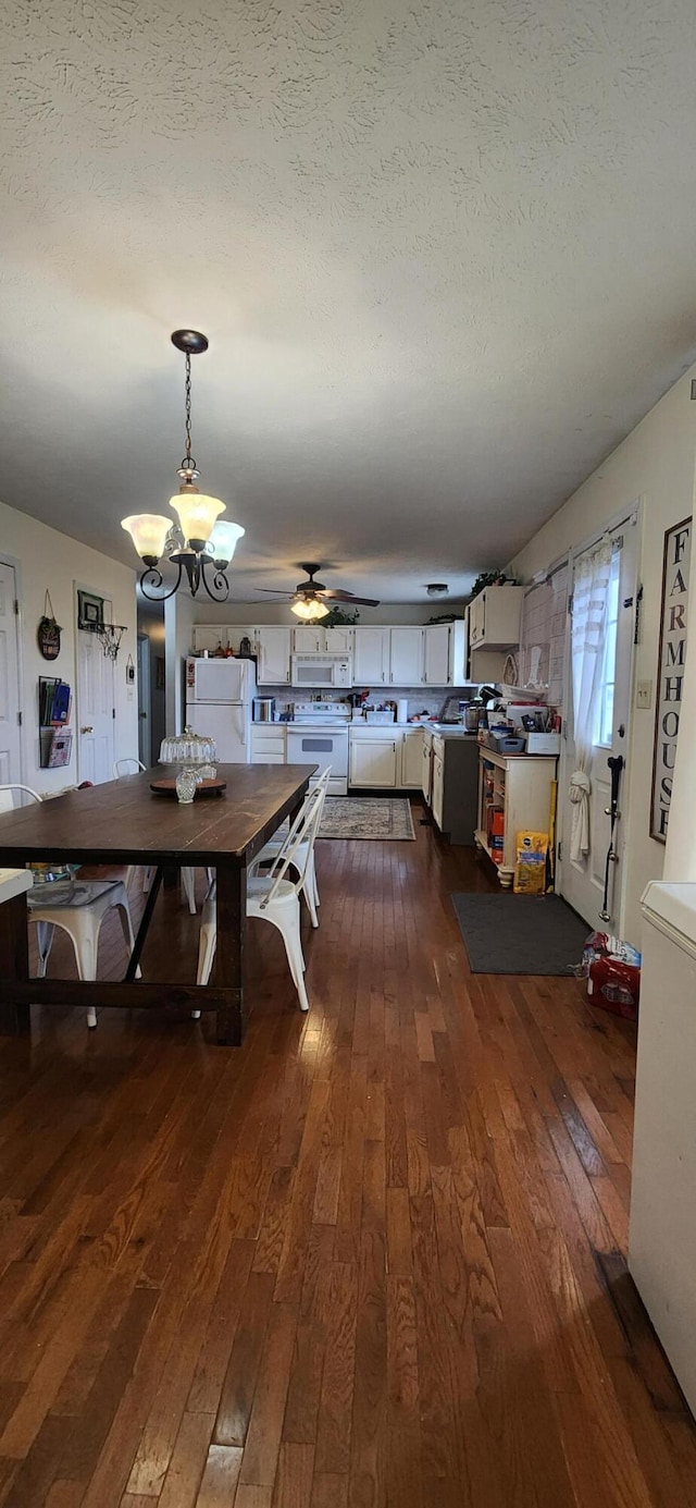 unfurnished dining area with a textured ceiling, ceiling fan with notable chandelier, and dark hardwood / wood-style floors