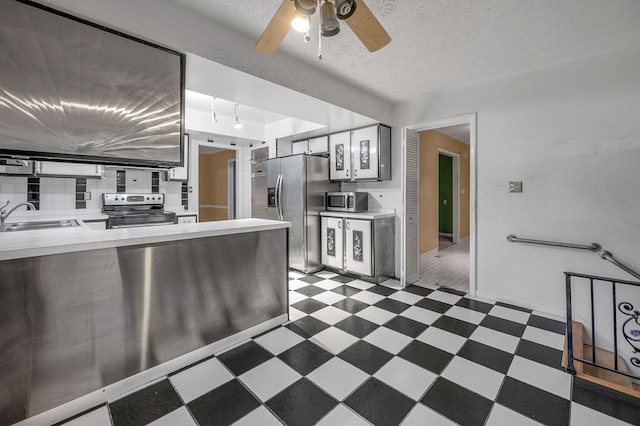 kitchen featuring a textured ceiling, ceiling fan, sink, and appliances with stainless steel finishes