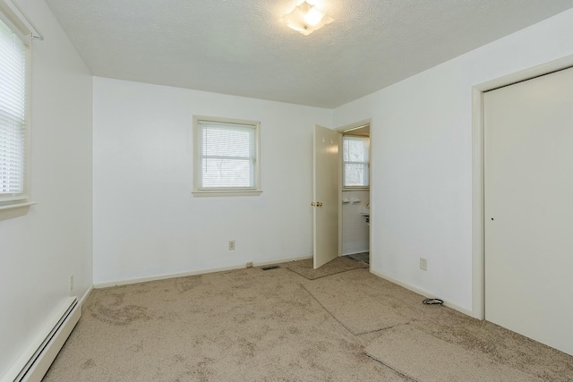 unfurnished bedroom featuring a baseboard heating unit, carpet, and multiple windows