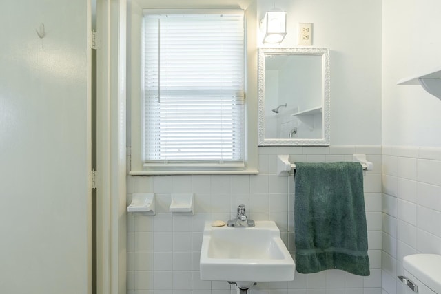 bathroom with toilet, tile walls, and sink