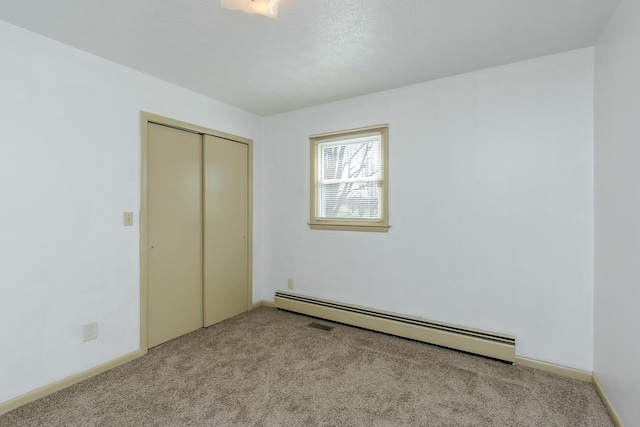 unfurnished bedroom with baseboard heating, light colored carpet, and a closet