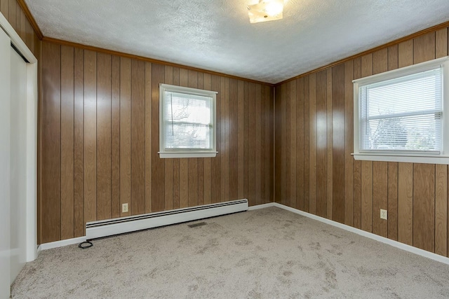 empty room featuring light carpet, a wealth of natural light, a textured ceiling, and a baseboard radiator