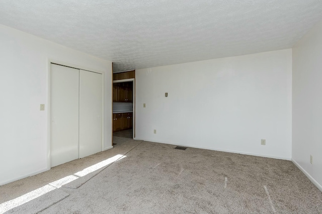 unfurnished bedroom with a textured ceiling, a closet, and light carpet