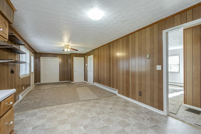 carpeted foyer with ceiling fan, a baseboard radiator, and wooden walls