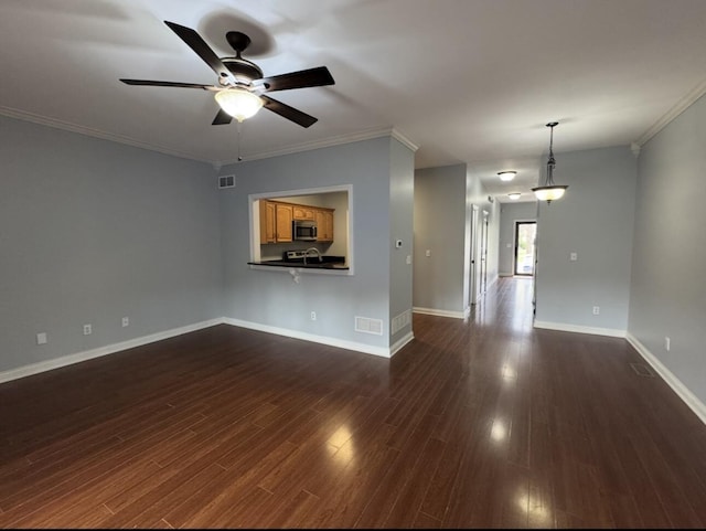 unfurnished living room featuring baseboards, dark wood finished floors, crown molding, visible vents, and ceiling fan