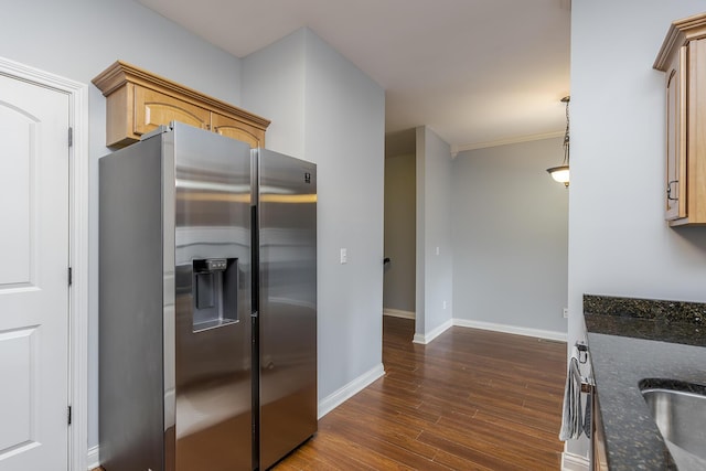 kitchen with dark stone counters, dark wood-style flooring, stainless steel fridge, hanging light fixtures, and baseboards