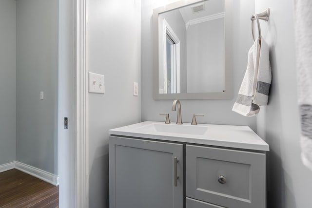 bathroom featuring visible vents, baseboards, crown molding, vanity, and wood finished floors